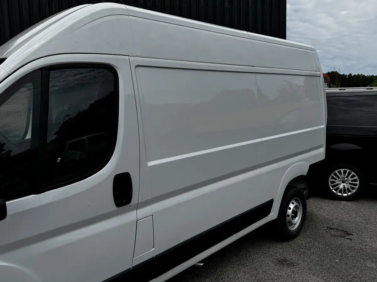 Vue de profil côté gauche d’un Peugeot Boxer Fourgon blanc, avec porte latérale coulissante et jante acier simple.