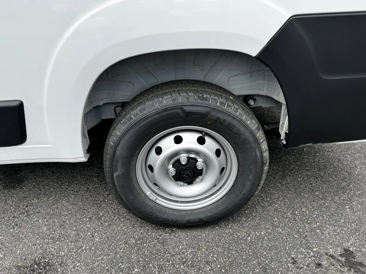 Gros plan sur la roue avant droite du Peugeot Boxer Fourgon blanc, avec jante acier et logo Peugeot central.