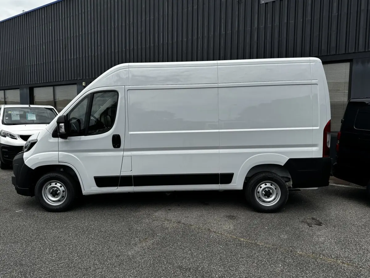 Vue de profil côté gauche d’un utilitaire Peugeot Boxer Fourgon blanc, version L2H2, avec protections noires sur les bas de caisse.