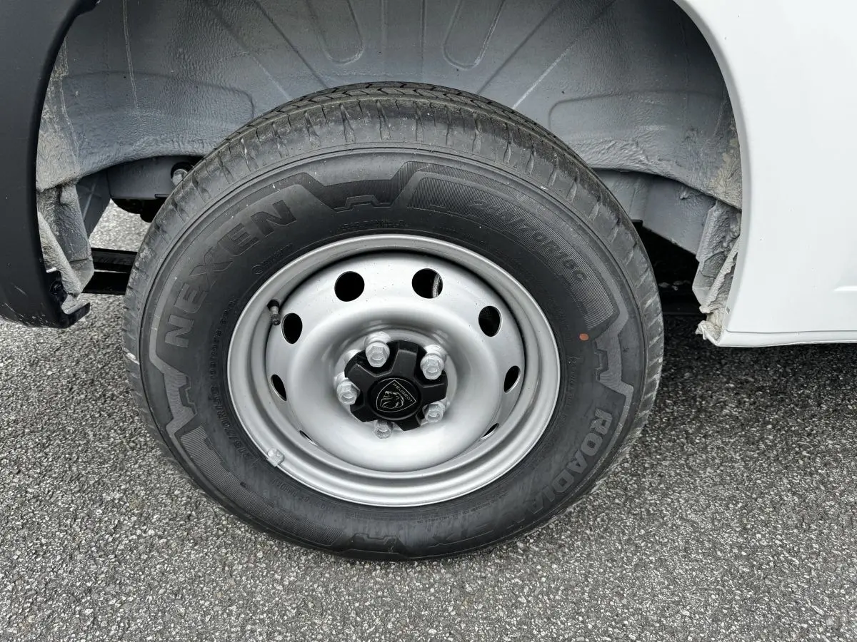 Gros plan sur la roue avant droite du Peugeot Boxer Fourgon blanc, avec jante acier et logo Peugeot au centre.