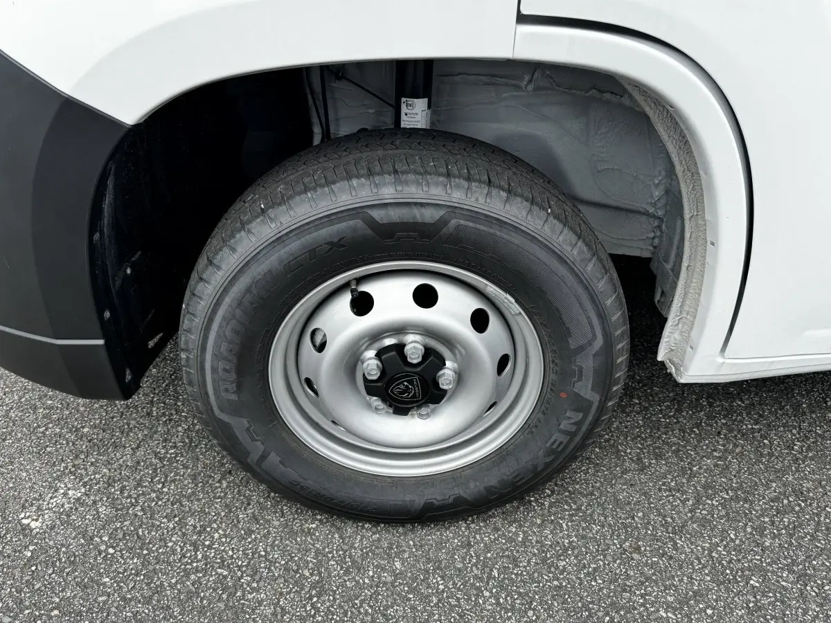 Gros plan sur la roue avant gauche du Peugeot Boxer Fourgon blanc, jante acier avec logo Peugeot central.