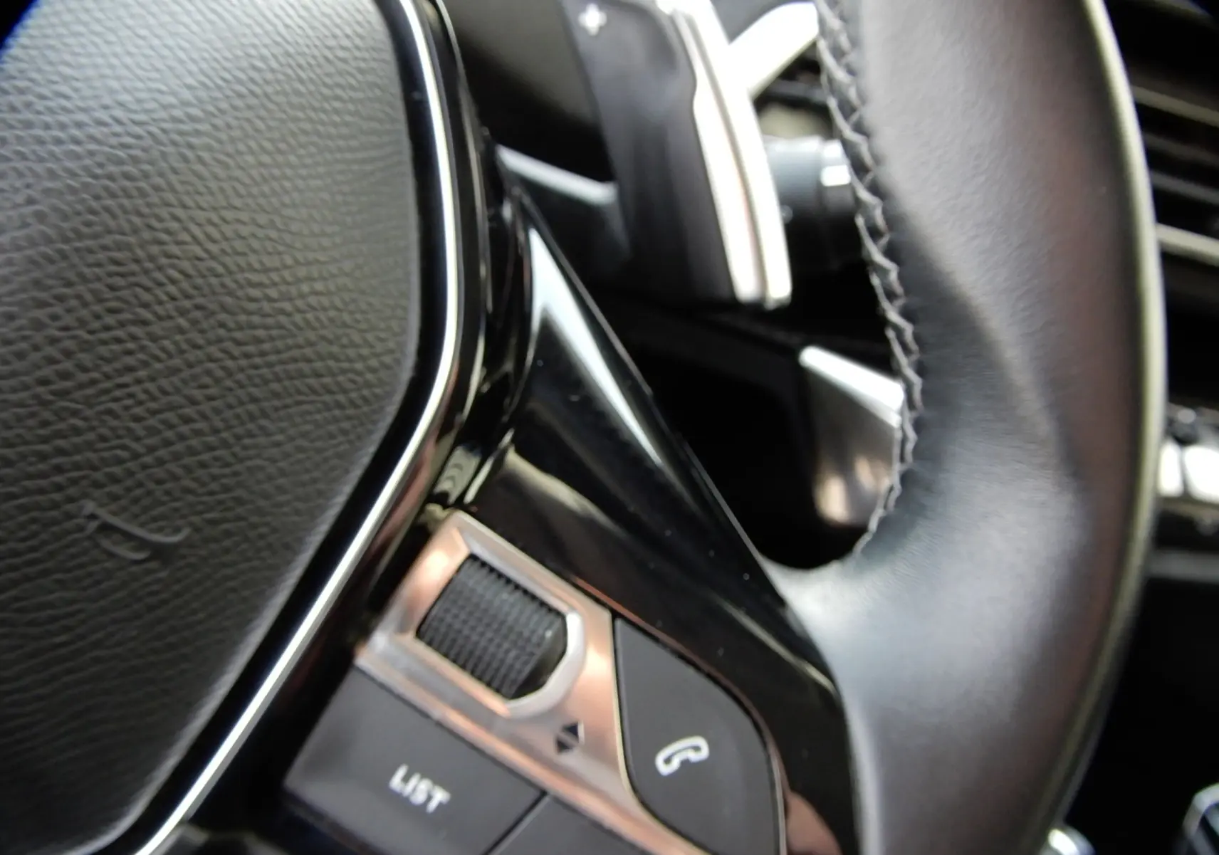 Gros plan sur les commandes du volant en cuir noir du Peugeot 5008 blanc nacré, version BlueHDi 130 EAT8 Allure.