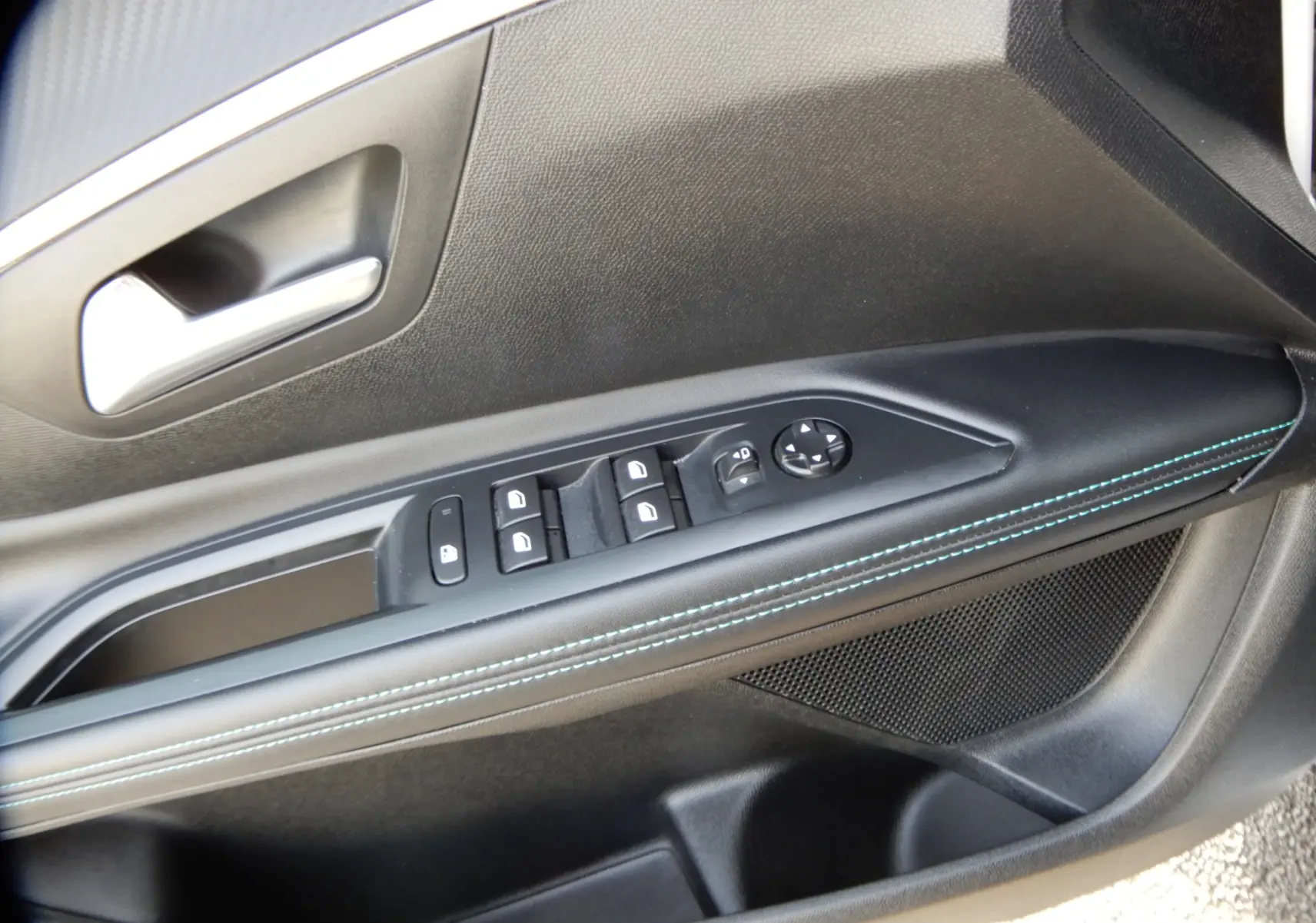 Gros plan sur la porte côté gauche du Peugeot 5008 blanc nacré, avec commandes électriques et surpiqûres bleues.