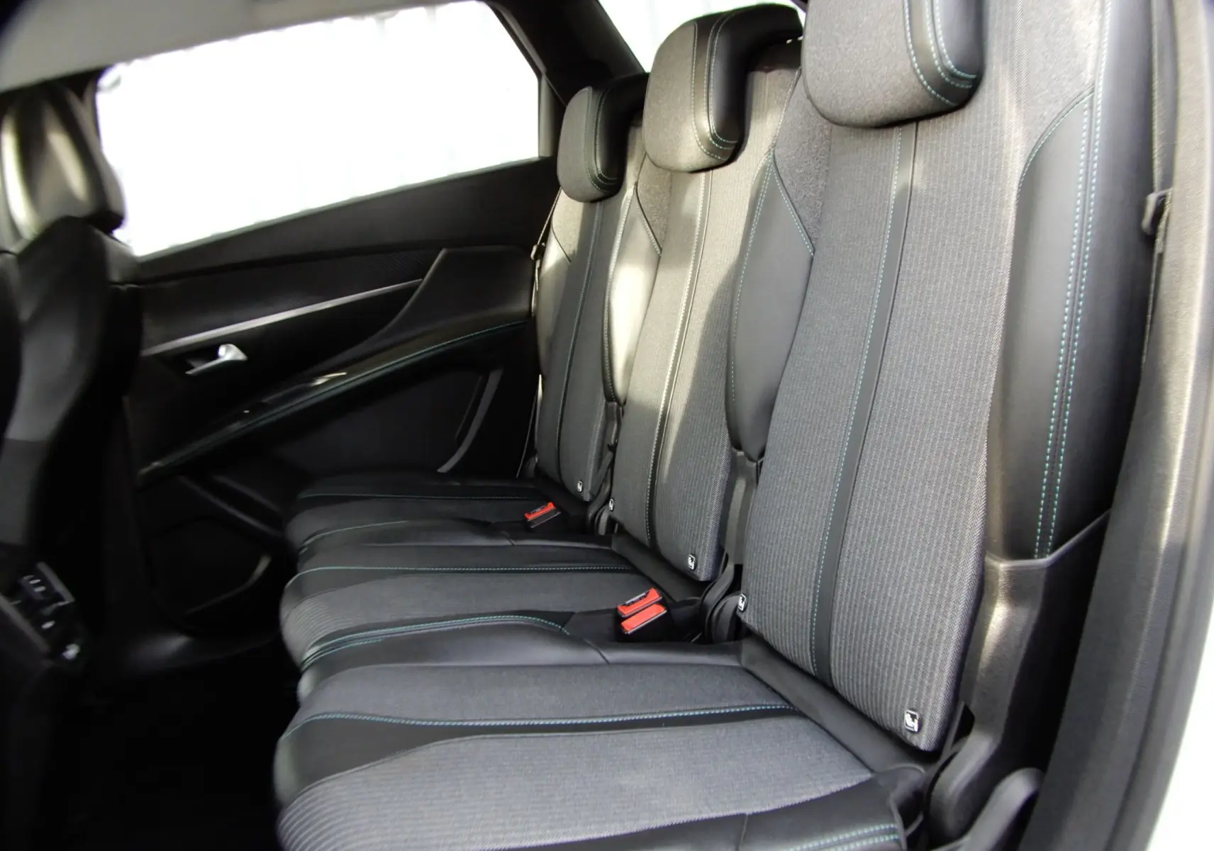 Vue latérale des sièges arrière noirs avec surpiqûres bleues du Peugeot 5008 blanc nacré 2021 version BlueHDi 130 Allure.