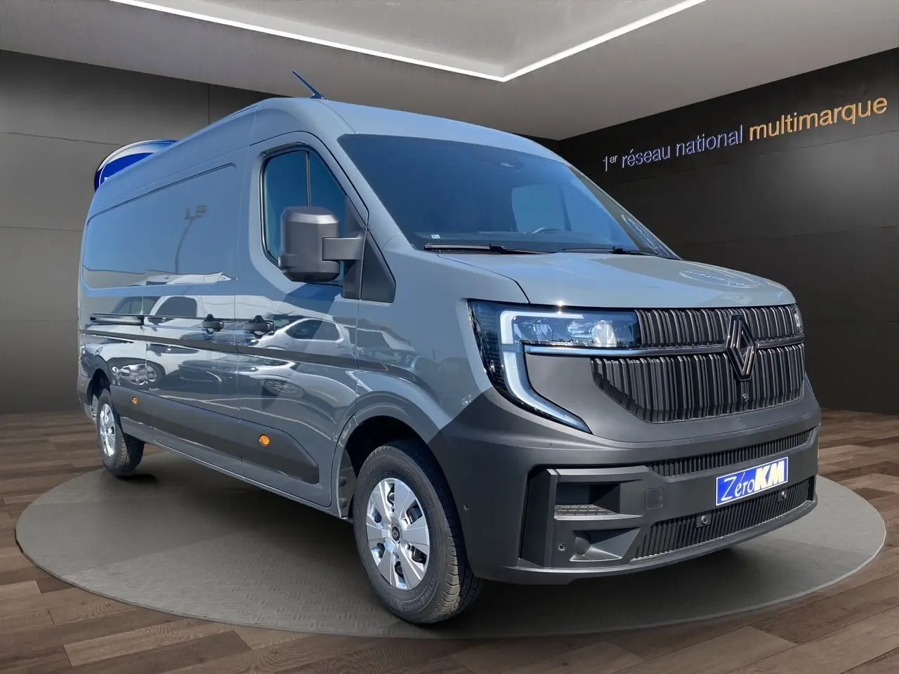 Renault Master gris urbain en 3/4 avant droit, fourgon utilitaire avec calandre noire et phares LED distinctifs.