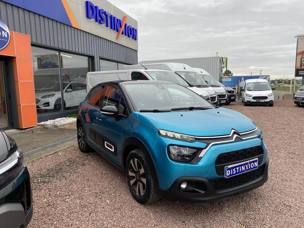 Citroën C3 2023 bleu Spring Azul avec toit noir, vue 3/4 avant sur parking devant concession Distinxion.