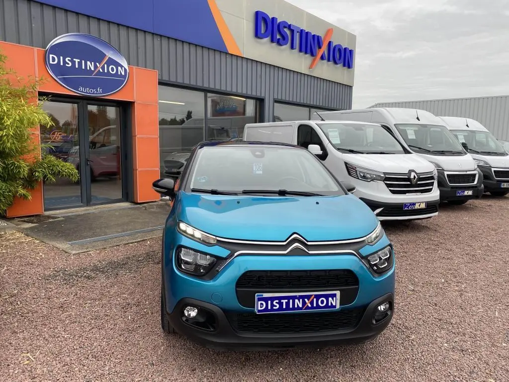 Vue frontale d'une Citroën C3 2023 bleu Spring Azul avec toit noir, devant un concessionnaire Distinxion.