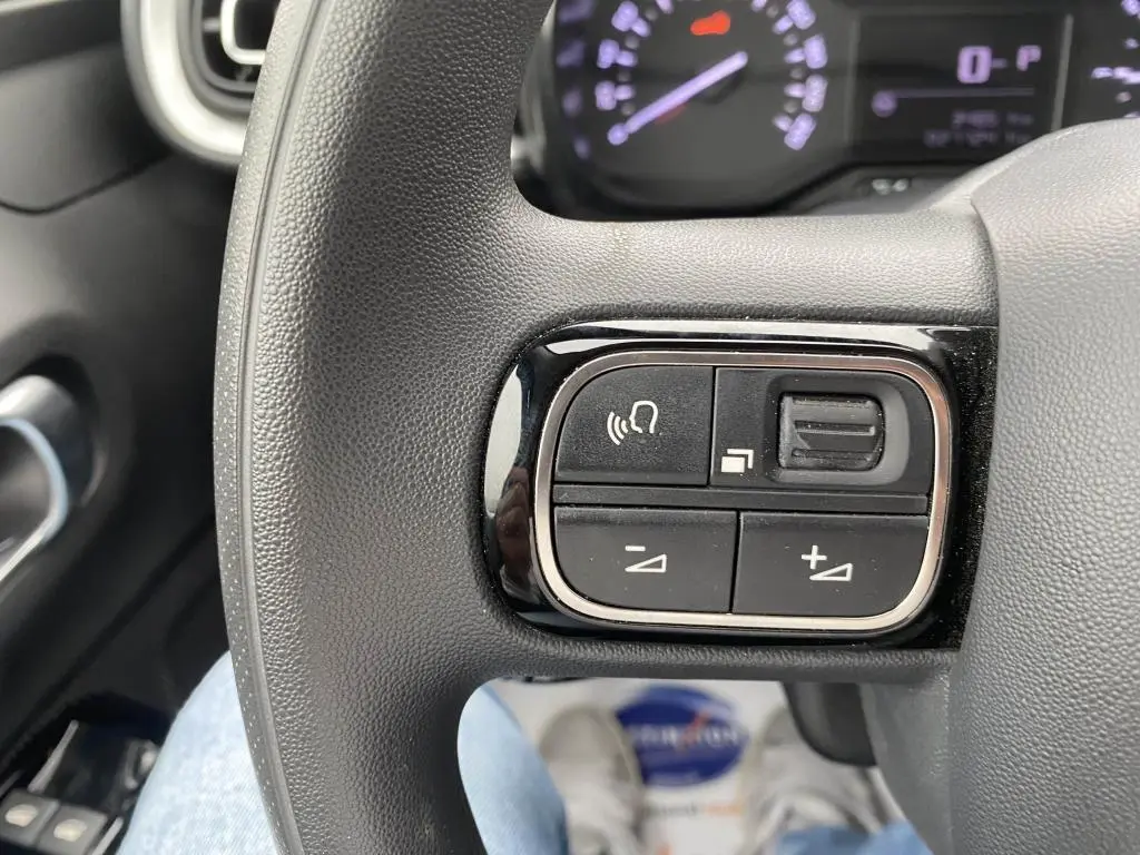 Gros plan sur les commandes audio au volant de la Citroën C3 2023, finition Shine, tableau de bord en arrière-plan.