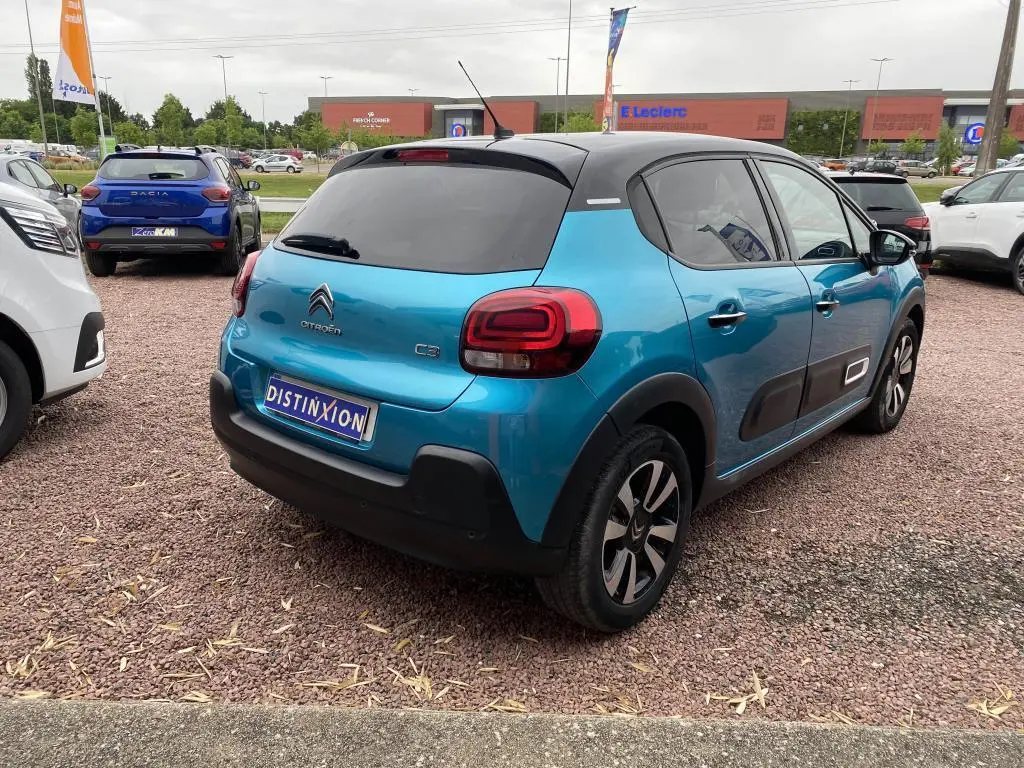 Vue 3/4 arrière droite d'une Citroën C3 2023 bleu Spring Azul avec toit noir et protections latérales noires.