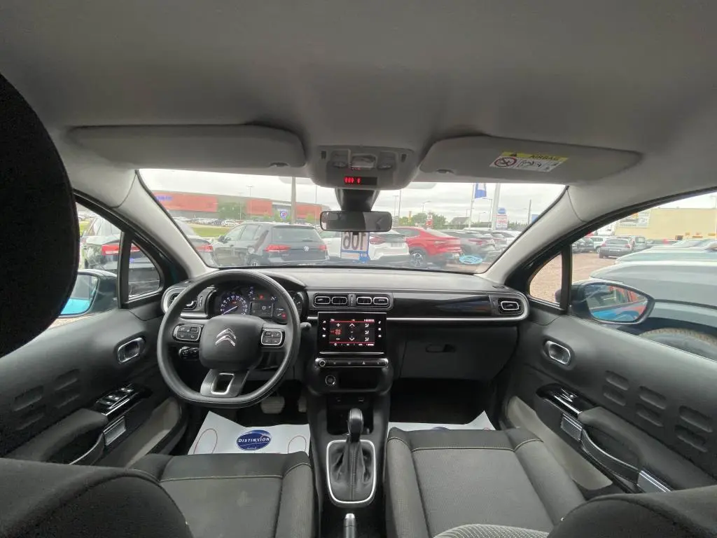 Vue intérieure frontale du poste de conduite d'une Citroën C3 2023 avec tableau de bord moderne et écran tactile central.