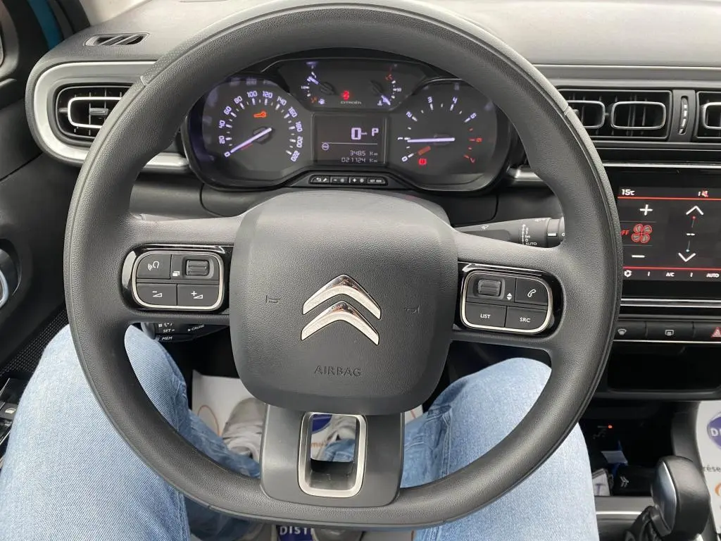 Vue rapprochée du volant multifonction noir de la Citroën C3 2023 avec tableau de bord et écran tactile en arrière-plan.