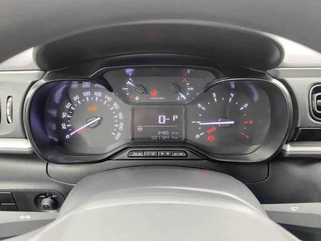 Tableau de bord de Citroën C3 2023 en vue frontale, affichant compteurs numériques et témoins lumineux allumés.