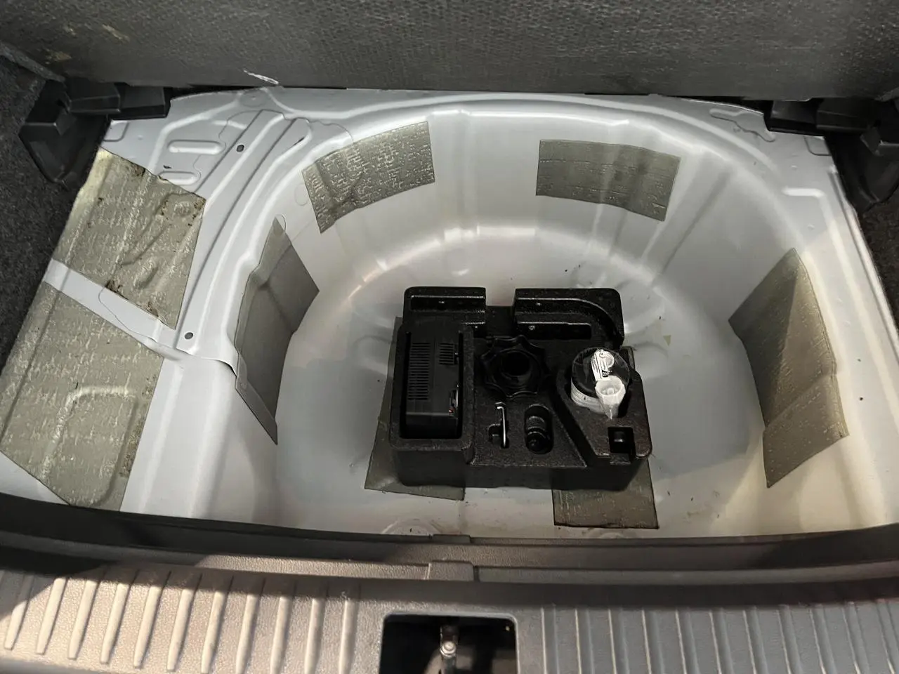 Coffre ouvert du SEAT Arona blanc Nevada 2024 montrant le rangement sous plancher avec kit de réparation pneus.