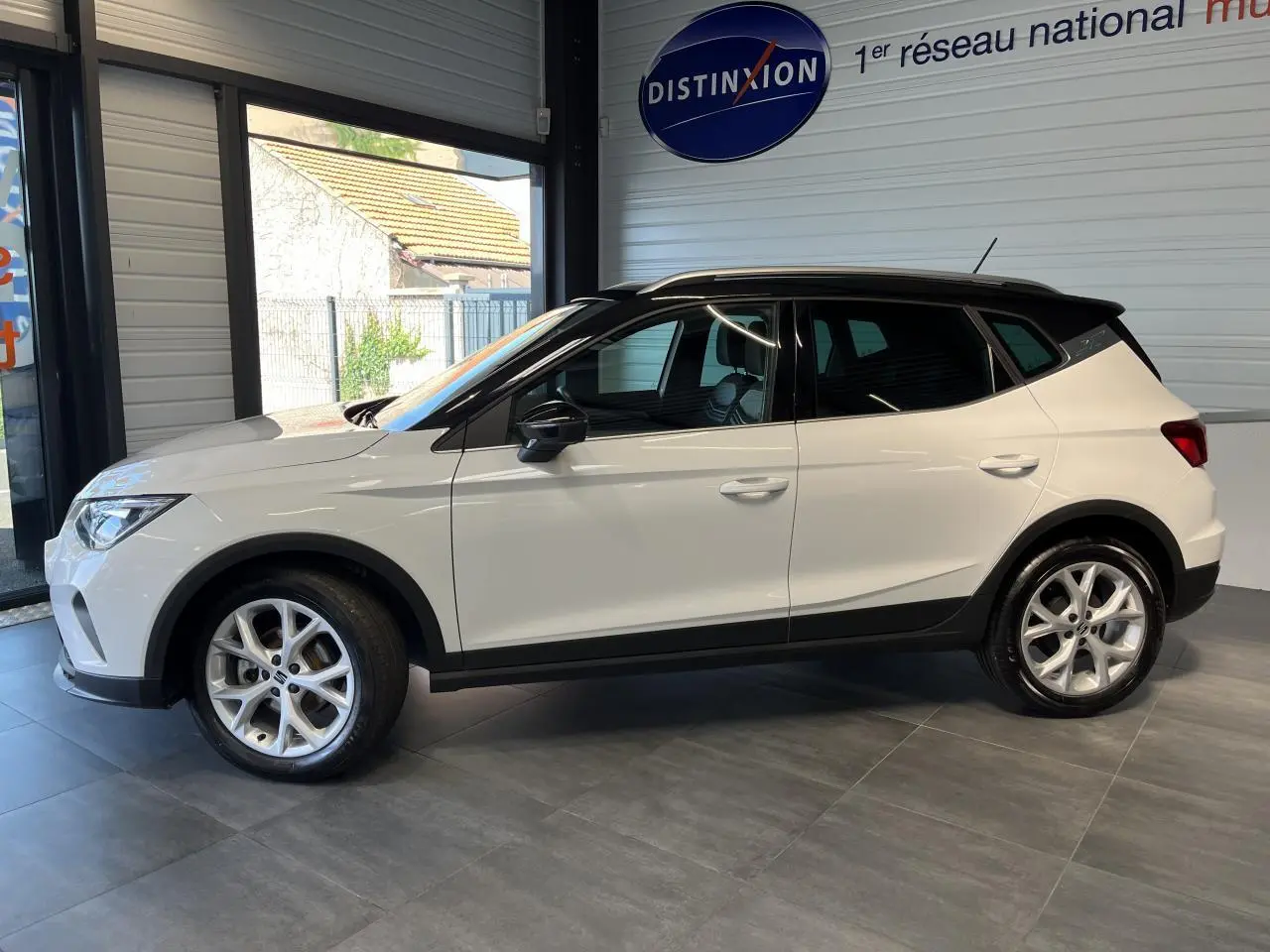 SEAT Arona blanc Nevada vu de profil côté gauche, avec toit noir et jantes alliage 16 pouces en showroom.