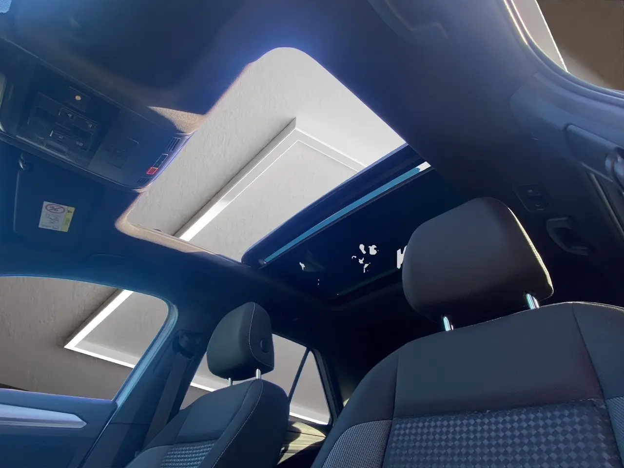 Intérieur du Volkswagen T-Roc 2021 avec toit ouvrant panoramique, sièges noirs et vue vers l'avant côté conducteur.