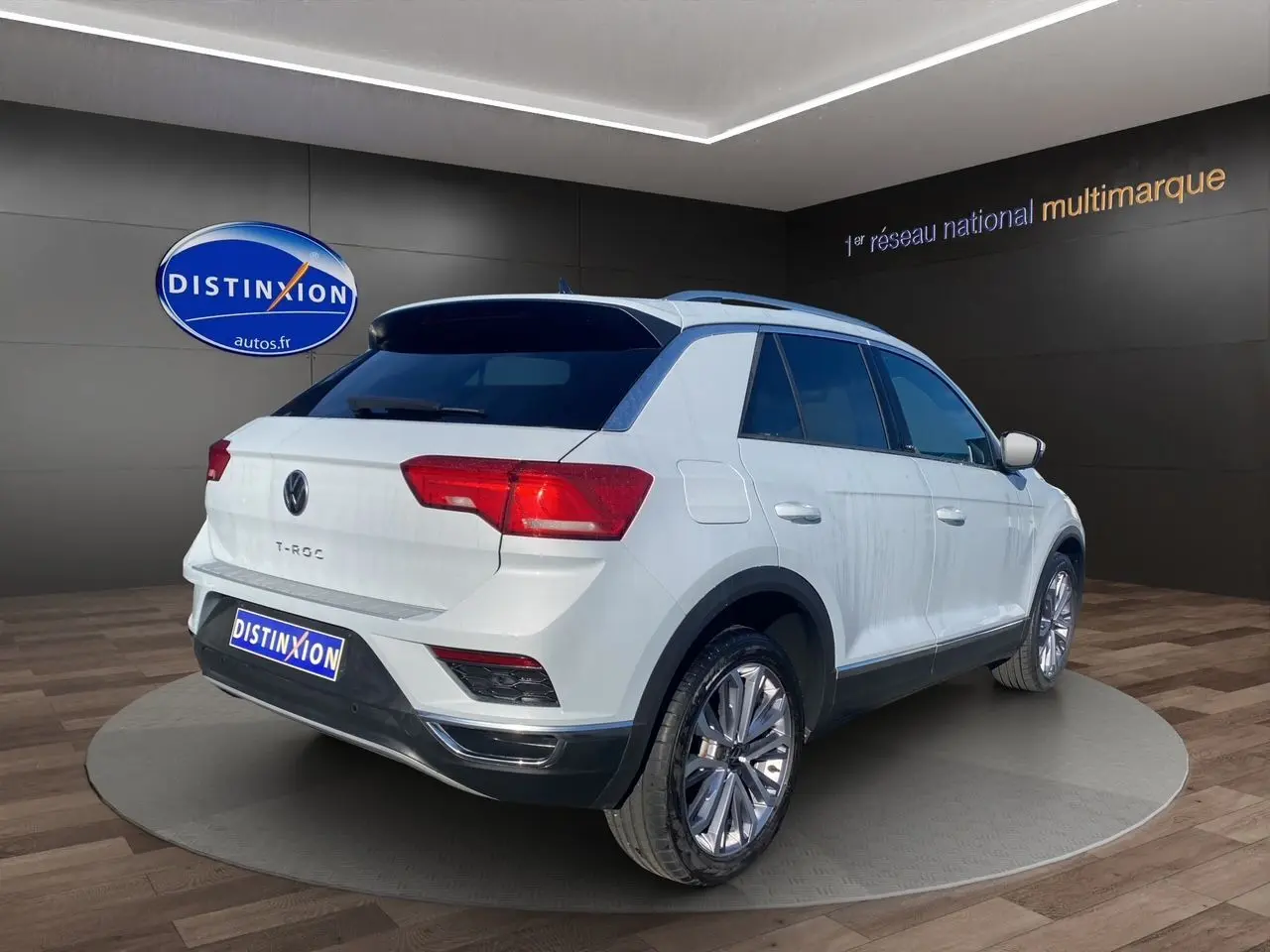 Volkswagen T-Roc blanc argenté vu en 3/4 arrière droit dans un showroom avec jantes alu 18 pouces.