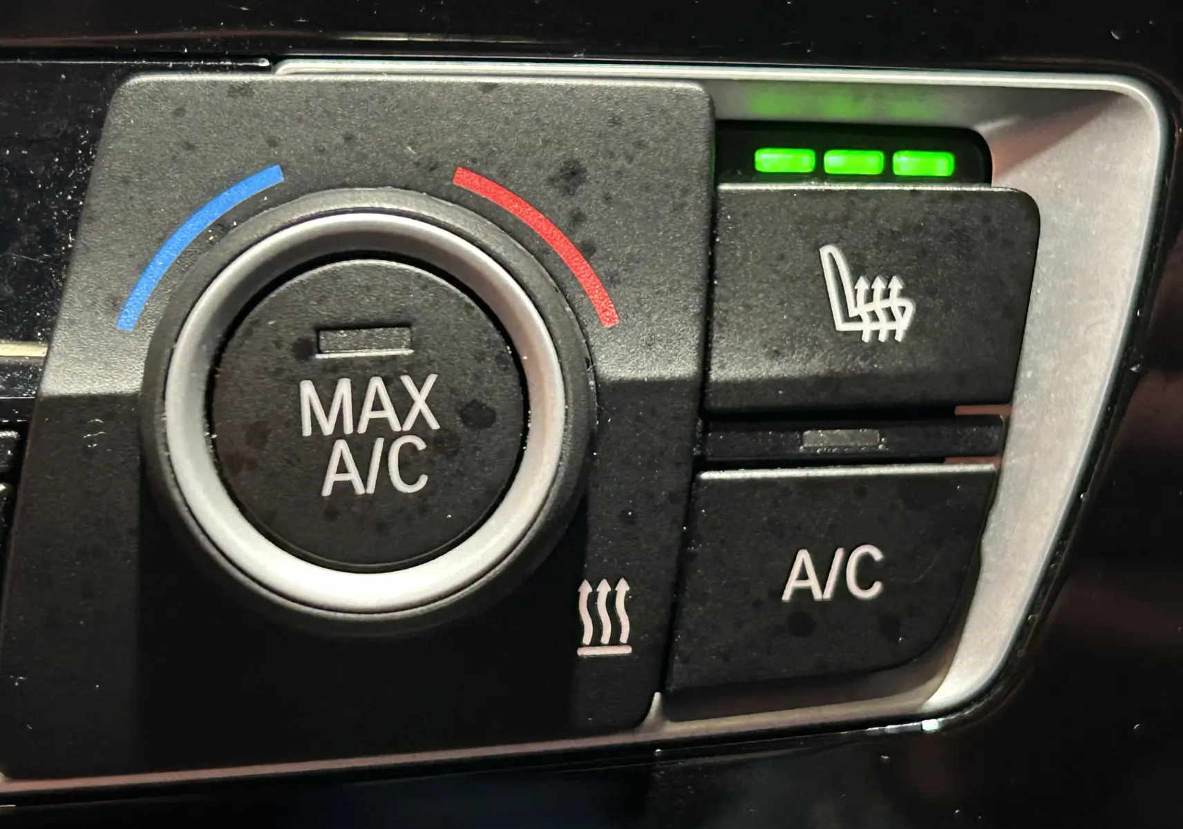 Gros plan sur les commandes de climatisation et siège chauffant de la BMW Série 1 120iA M Sport 2019.