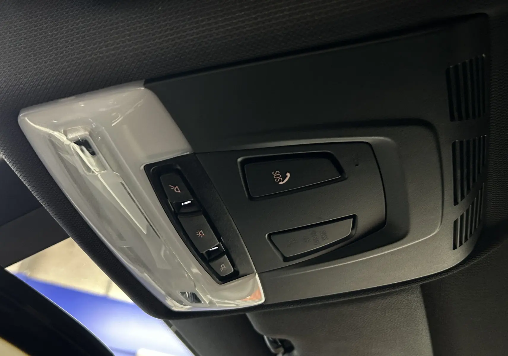 Vue en gros plan du plafonnier noir avec commandes SOS et éclairage intérieur de la BMW Série 1 blanche 2019.
