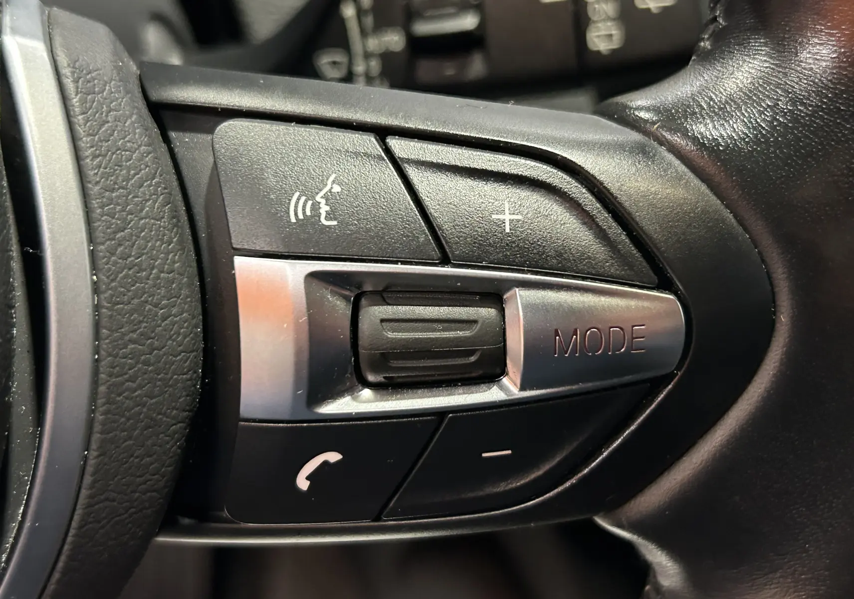 Gros plan sur les commandes multifonctions au volant en cuir noir de la BMW Série 1 120iA M Sport 2019.