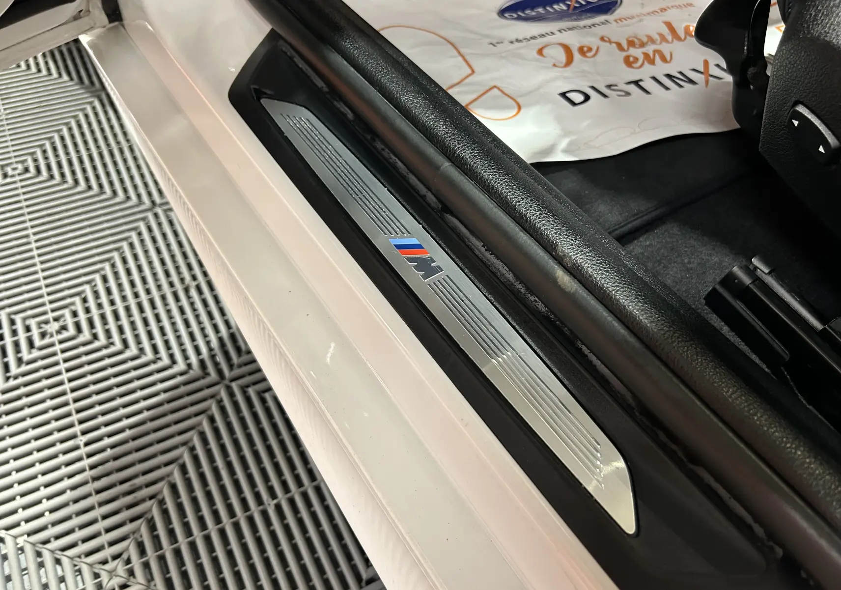 Seuil de porte côté conducteur blanc de BMW Série 1 120iA M Sport avec logo M coloré visible.