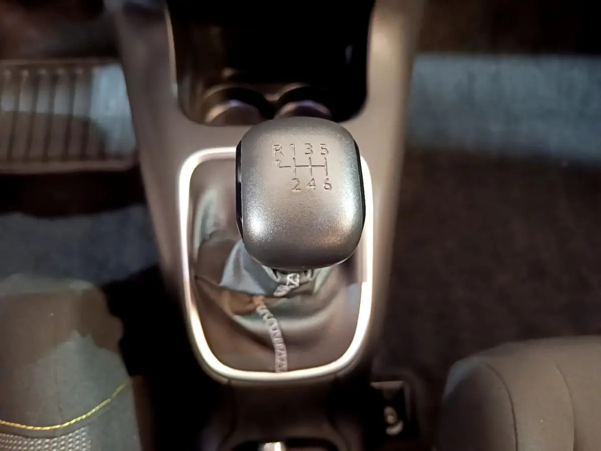 Le levier de vitesses manuel gris de la Citroën C3 blanche, vu en gros plan depuis l'intérieur.