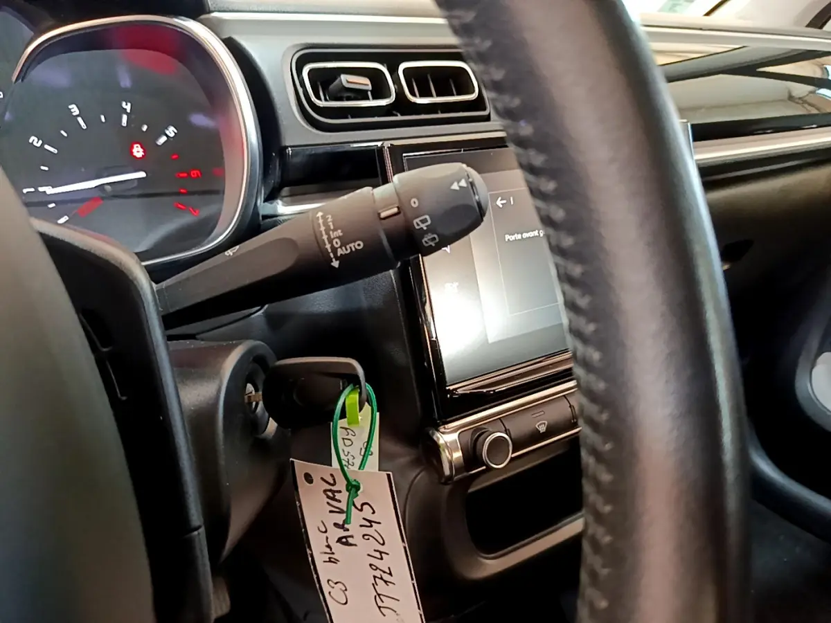 Vue rapprochée du tableau de bord et volant cuir noir de la Citroën C3 blanche avec écran tactile central allumé.