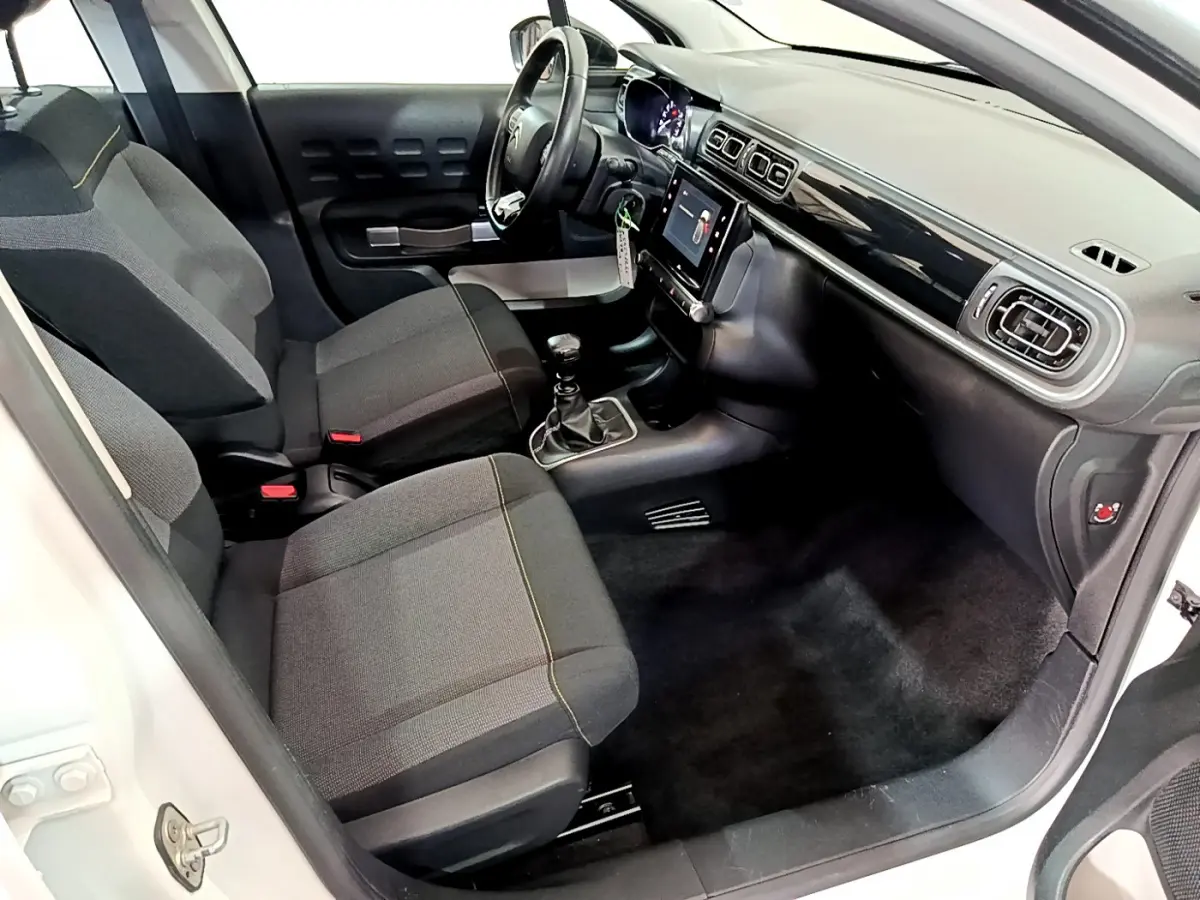 Intérieur avant droit de la Citroën C3 blanche 2019, montrant sièges tissu, tableau de bord avec écran tactile et volant cuir.