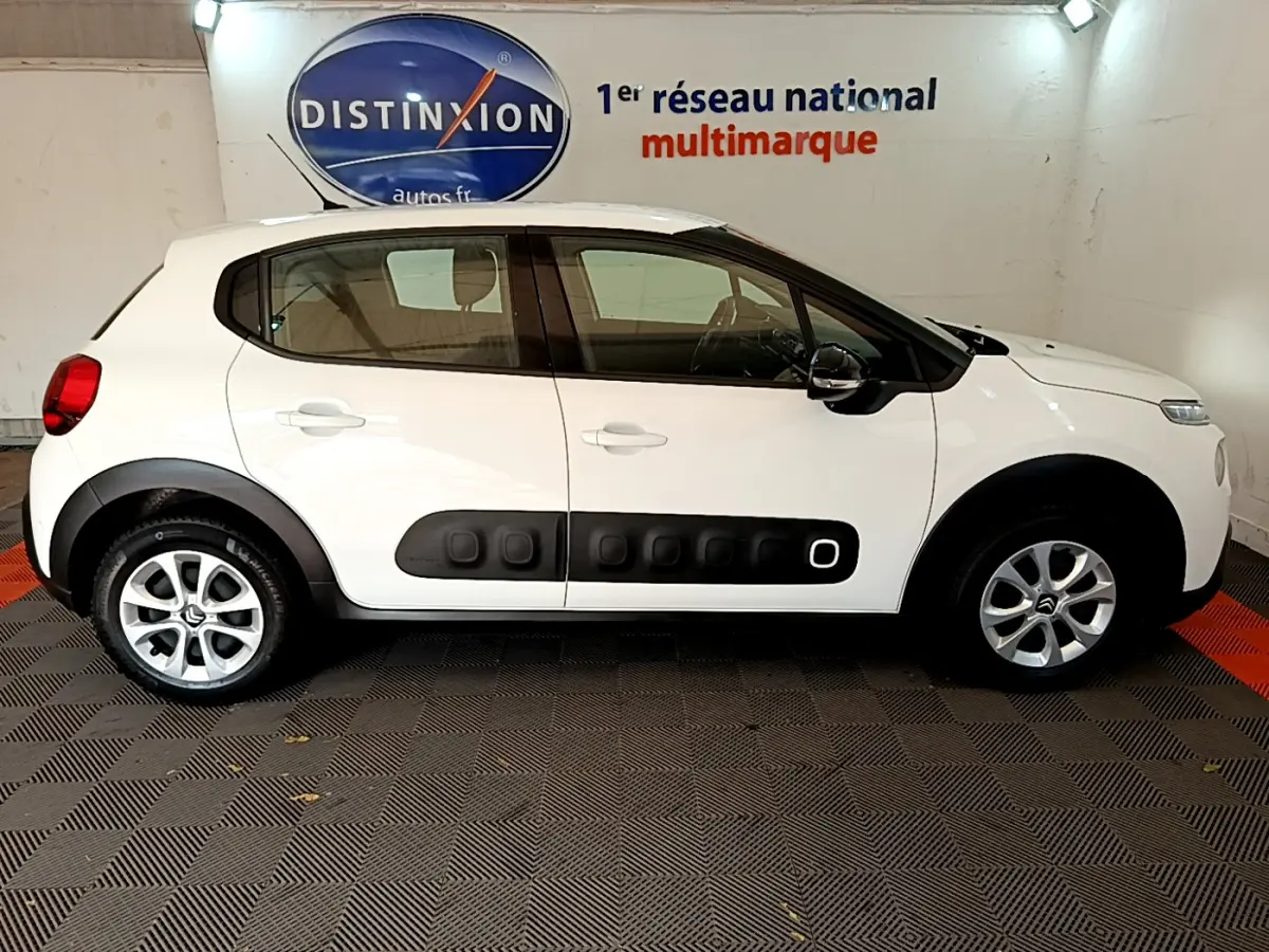 Profil côté gauche d'une Citroën C3 blanche de 2019 avec protections latérales noires et jantes alliage.