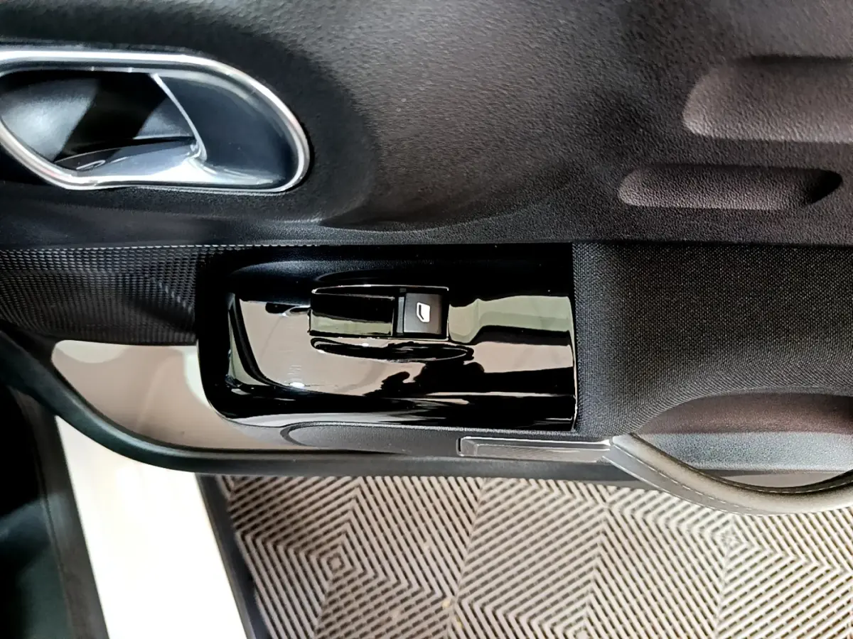 Gros plan sur la commande de lève-vitre côté gauche de la porte intérieure noire d'une Citroën C3 blanche 2019.