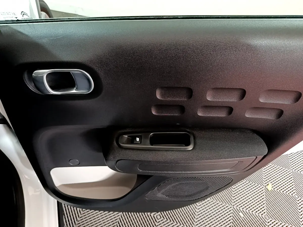 Gros plan sur la porte côté gauche blanche et noire de la Citroën C3 PureTech 110 Shine Business 2019, avec poignée et commande fenêtre.