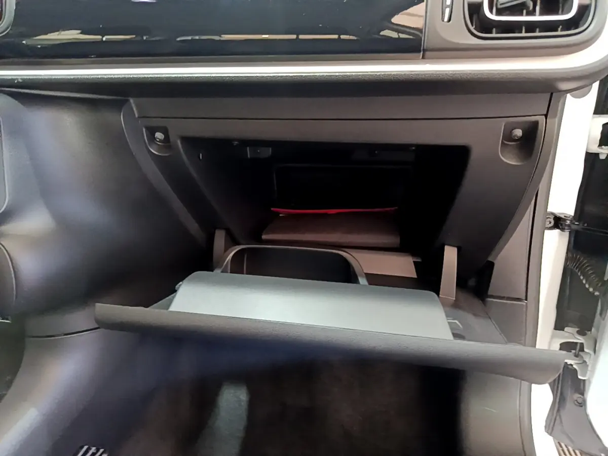 Gros plan sur la boîte à gants ouverte côté passager de la Citroën C3 blanche, intérieur noir.