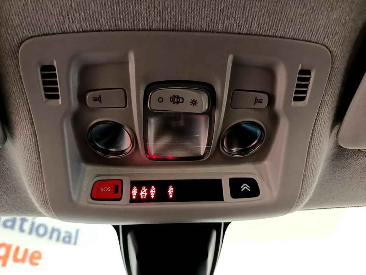 Vue en gros plan du plafonnier intérieur avec commandes d'éclairage et bouton SOS de la Citroën C3 blanche de 2019.
