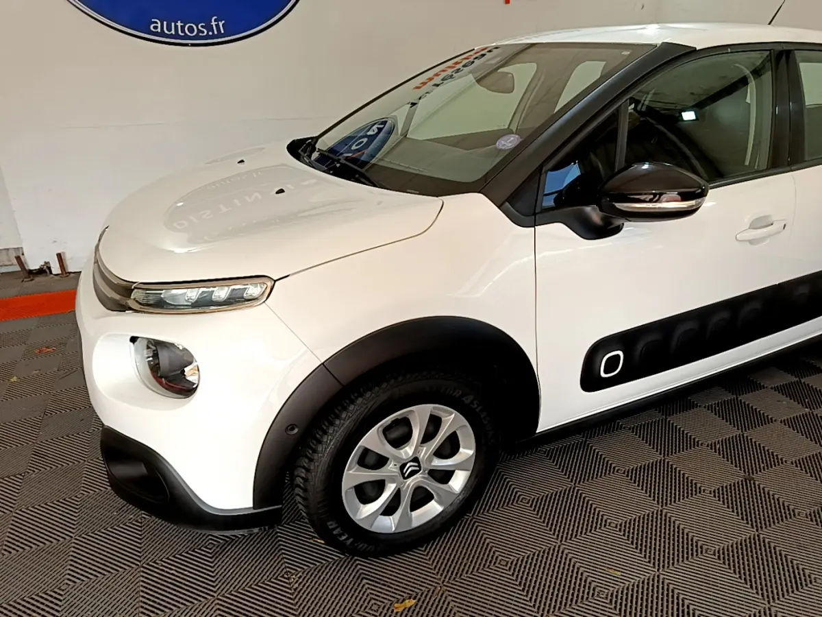 Vue 3/4 avant gauche d'une Citroën C3 blanche avec protections latérales noires et jantes alliage.