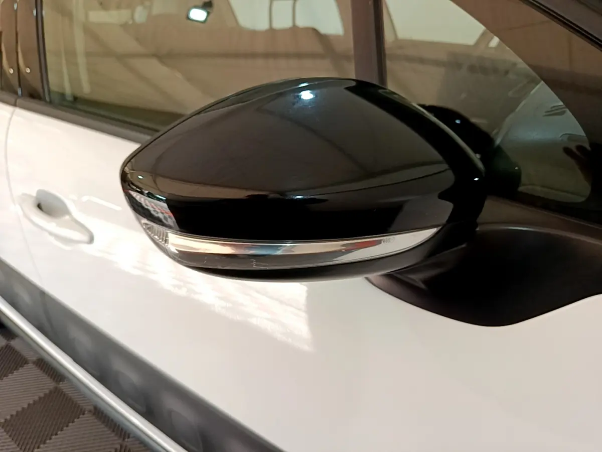 Rétroviseur noir avec clignotant intégré côté gauche d'une Citroën C3 blanche vue de près.