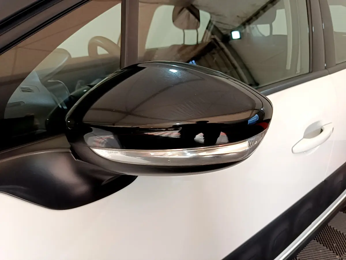 Rétroviseur noir brillant côté gauche d'une Citroën C3 blanche, avec clignotant intégré visible.