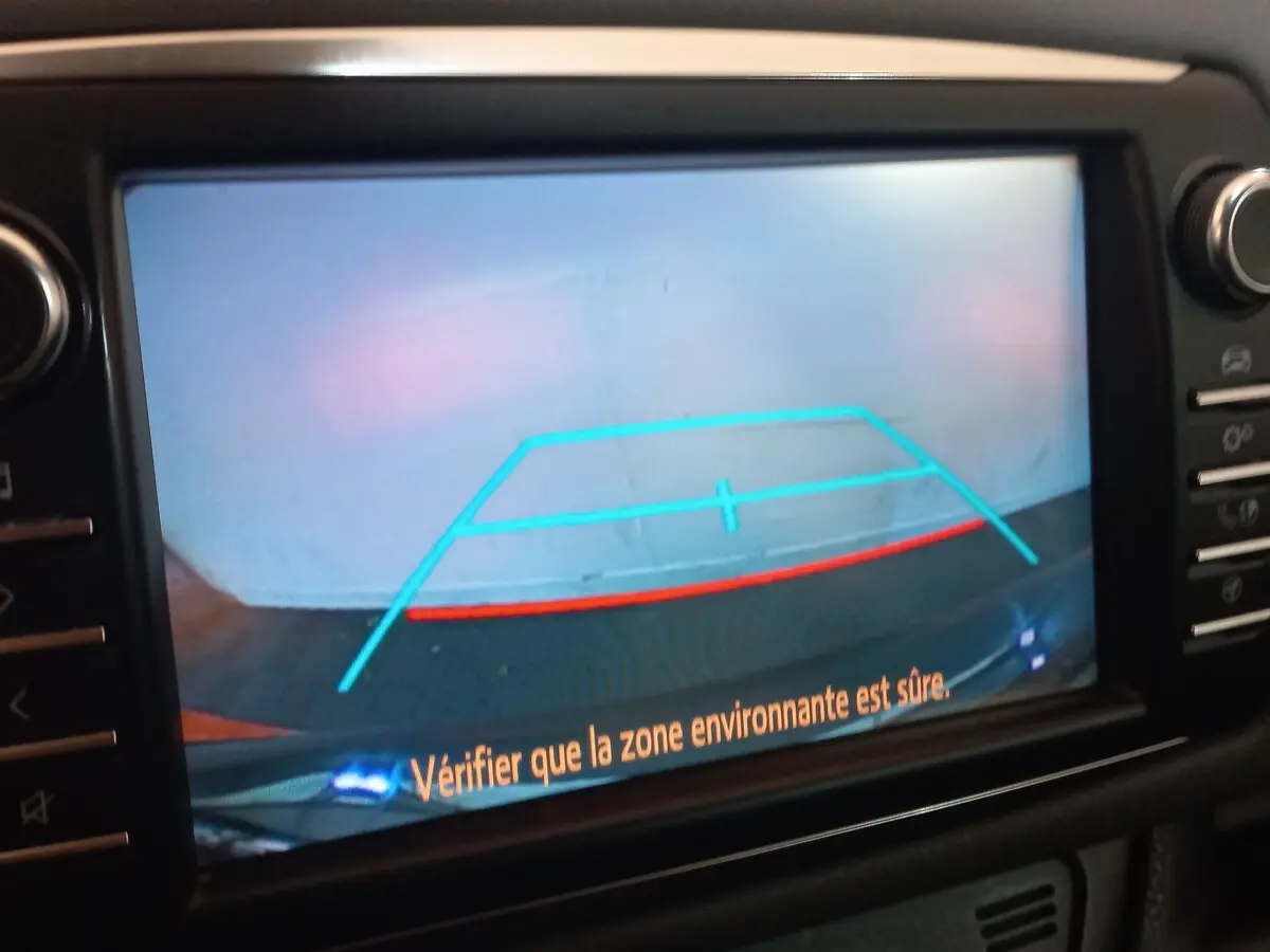 Écran tactile intérieur affichant la caméra de recul de la Toyota Yaris hybride noire avec repères de stationnement colorés.