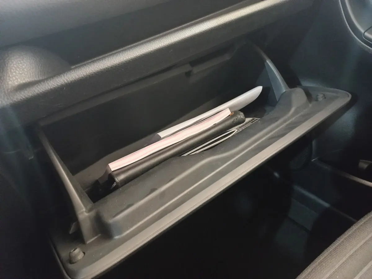 Gros plan sur la boîte à gants ouverte de la Toyota Yaris noire, montrant des documents à l'intérieur.