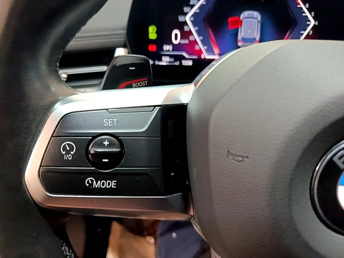 Gros plan sur le côté gauche du volant cuir alu du BMW X1 xDrive23i M Sport 2023 avec commandes de régulateur.