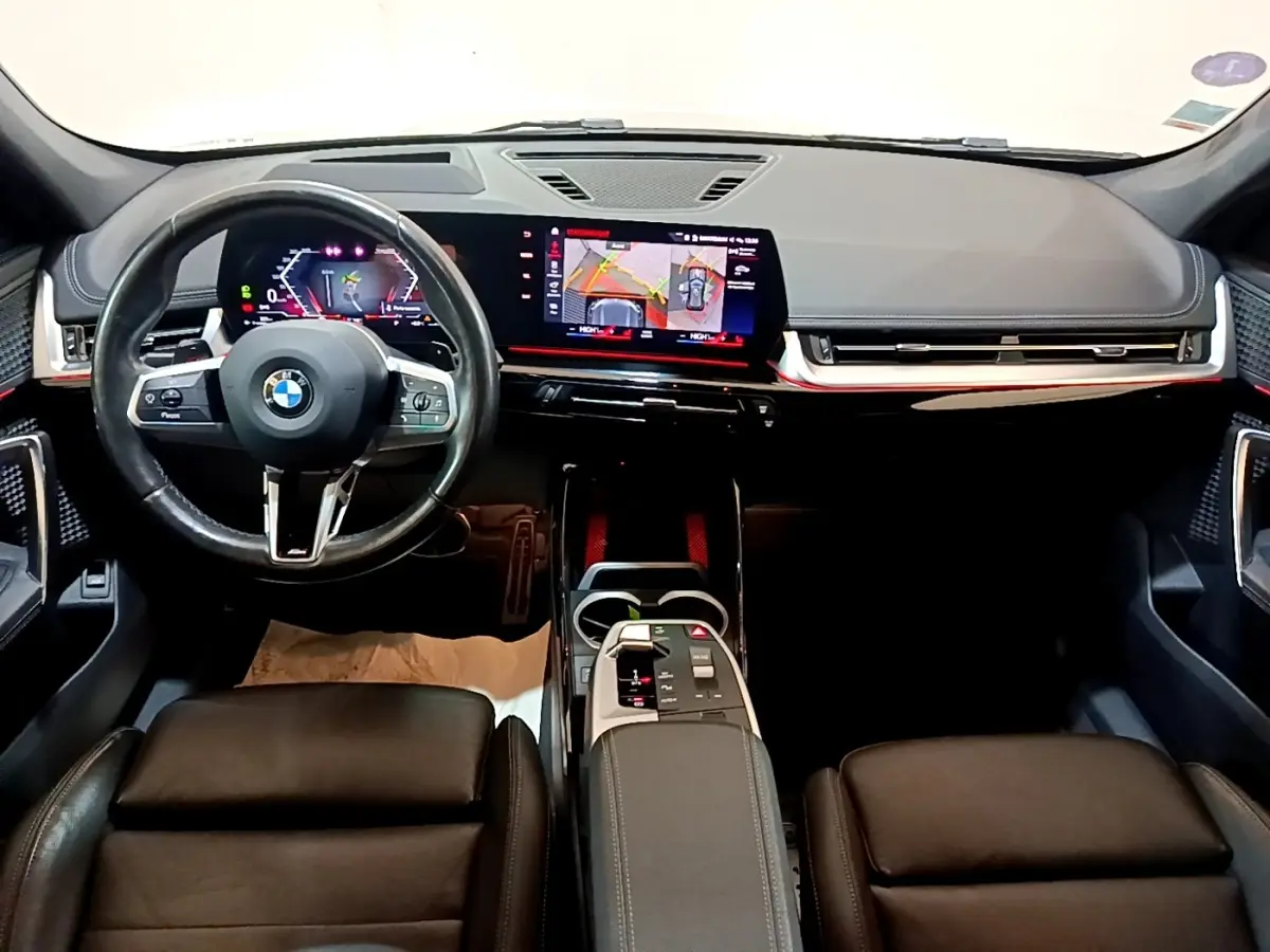 Vue intérieure avant du BMW X1 xDrive23i M Sport 2023, tableau de bord numérique et écran tactile central lumineux.