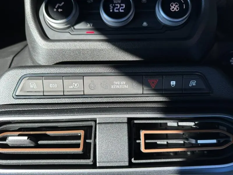 Vue rapprochée de la console centrale du Dacia Jogger blanc, mettant en valeur les boutons de commandes et les aérateurs noirs avec insertions marron.
