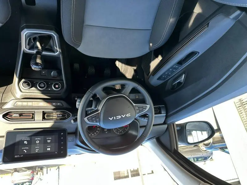 Vue intérieure du poste de conduite du Dacia Jogger blanc, avec volant multifonction et tableau de bord numérique.