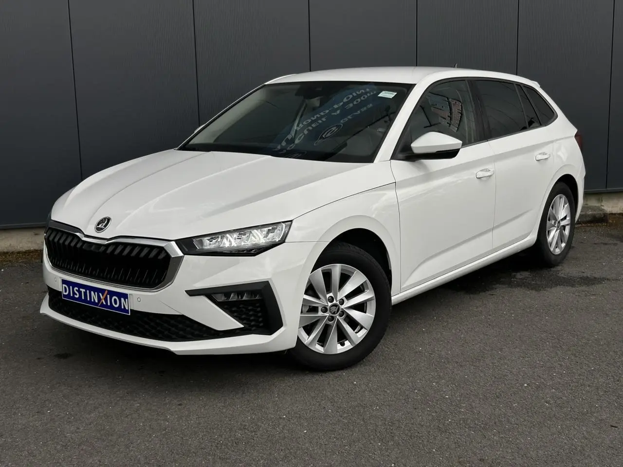 Vue 3/4 avant droite d'une Skoda Scala blanc Candy avec jantes alliage et vitres latérales surteintées.