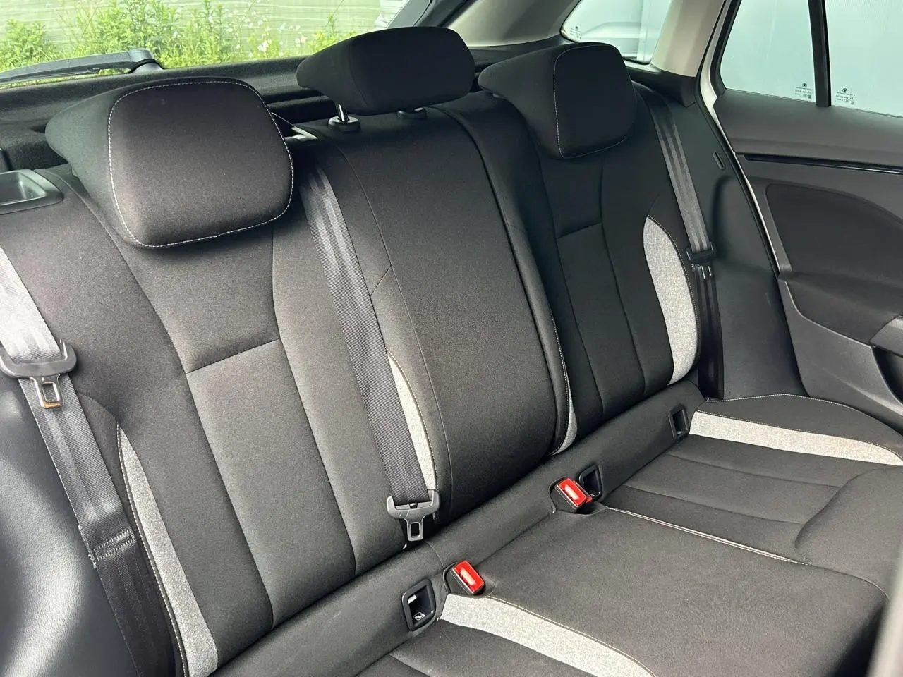 Vue intérieure de la banquette arrière noire avec surpiqûres claires et ceintures de sécurité dans une Skoda Scala blanche.