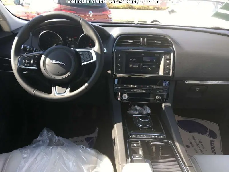 Intérieur noir de la Jaguar F-PACE 2018 vu de face, volant cuir avec logo Jaguar et écran tactile central.