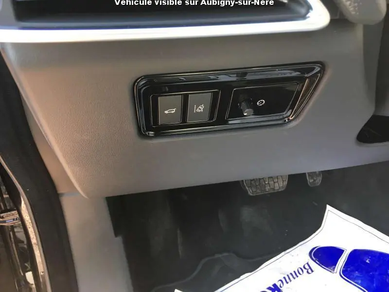 Détail des commandes sous le tableau de bord côté gauche du Jaguar F-PACE noir, avec pédales visibles.