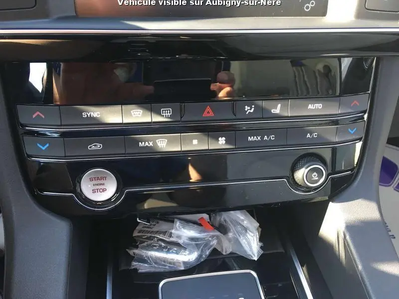 Vue rapprochée de la console centrale noire du Jaguar F-PACE 2018 avec commandes climatisation et bouton start/stop.
