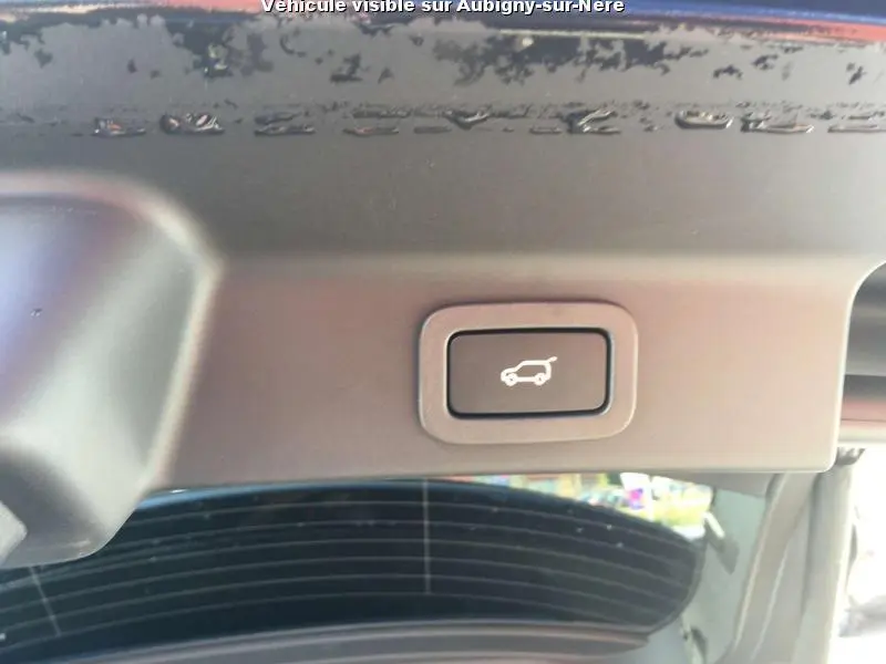 Bouton d'ouverture électrique du coffre sur le hayon intérieur d'un Jaguar F-PACE noir, vue rapprochée.