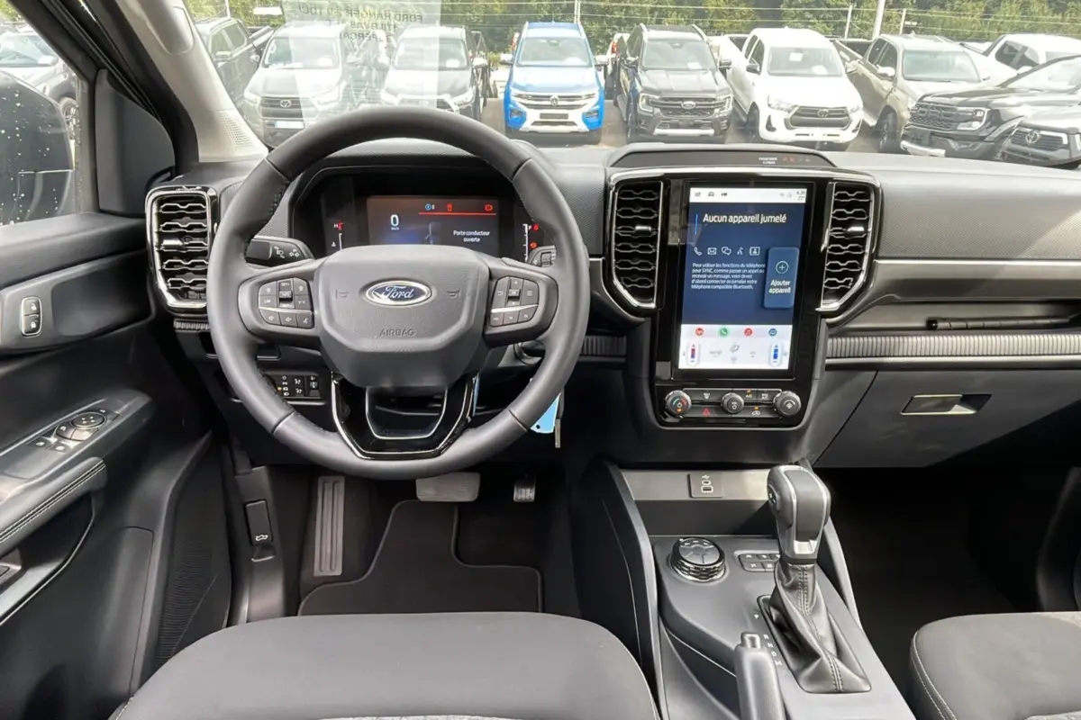 Vue intérieure du Ford Ranger 2025 gris carbone, tableau de bord moderne avec écran tactile vertical et volant multifonction.