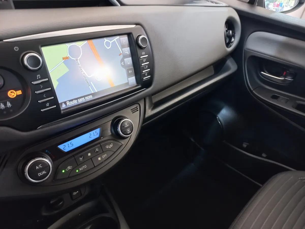 Vue intérieure côté passager de la Toyota Yaris 2019 avec écran tactile de navigation et commande de climatisation digitale.