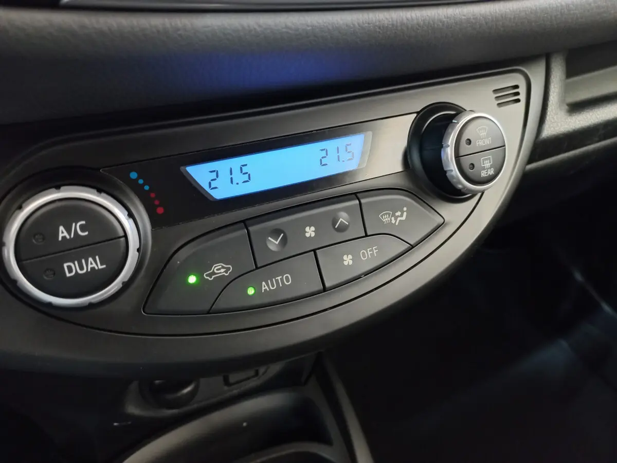 Gros plan sur la commande de climatisation bi-zone avec affichage digital à 21,5°C dans une Toyota Yaris blanche 2019.
